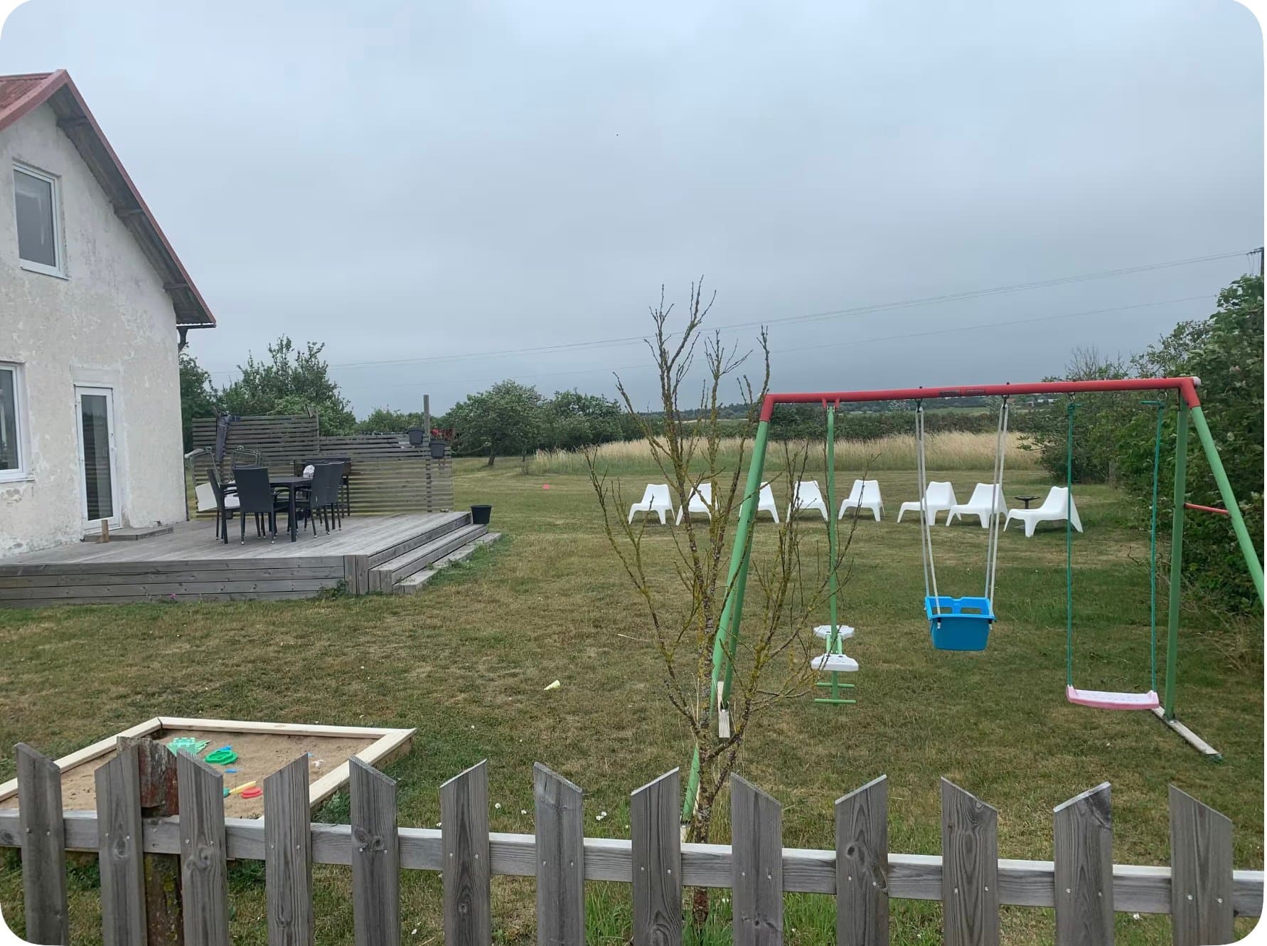 Vacker trädgård med gungor, sandlåda och gräsmatta - perfekt för familjer. Uteplats med möbler vid stugan för avkoppling och naturupplevelser.